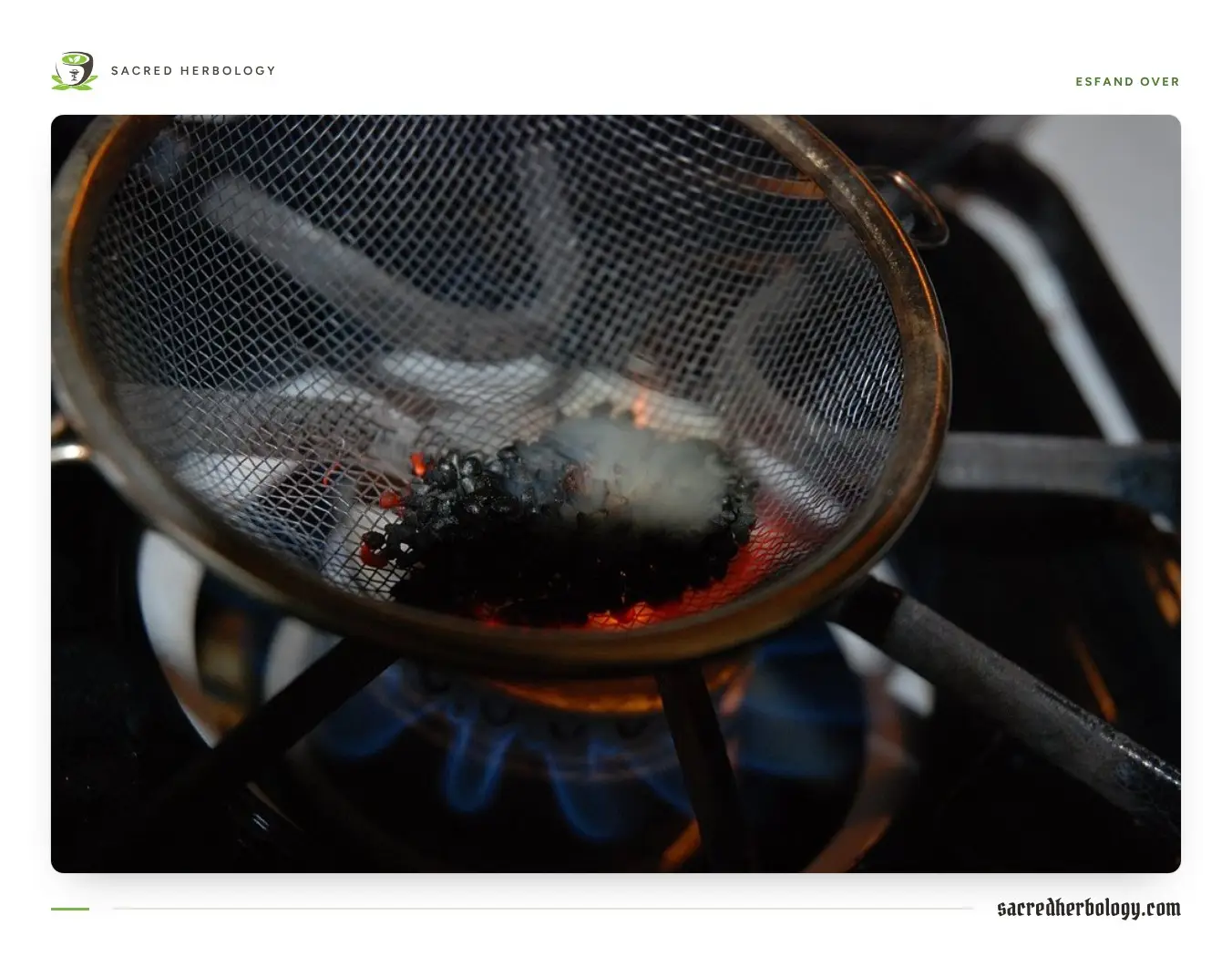 Dark seeds smouldering and giving off white smoke in a small wire-mesh strainer held over the blue flame of a gas stove